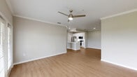 Located in Orlando, FL, this well-appointed 2-bedroom, 3-bathroom single-story home offers a thoughtfully designed open-concept layout. The combined kitchen and living area serves as the heart of the home, featuring light wood-tone flooring, crown molding, and a ceiling fan with integrated lighting. French doors in the living room flood the space with natural light and open to an outdoor view of lush green surroundings. The kitchen is outfitted with crisp white shaker-style cabinetry, white quartz countertops, and a full suite of stainless steel appliances including a refrigerator, electric range, and over-the-range microwave. The primary bedroom is a generously sized retreat with a ceiling fan, mirrored closet doors, and a dedicated walk-in closet featuring wire shelving on multiple levels. The en-suite primary bathroom includes a dual-sink vanity with white cabinetry and a separate water closet. The second bedroom offers a sliding mirrored closet and a window with outdoor views. Additional bathrooms include a tub-shower combination. A dedicated laundry area houses a full-size washer and water heater. Throughout the home, consistent light wood flooring and a neutral warm-gray palette create a cohesive, modern aesthetic.