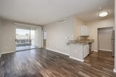 Located at 8465 Regents Rd in San Diego, CA, this thoughtfully designed one-bedroom, one-bathroom residence offers a efficient and functional single-floor layout. The open-concept living room and kitchen area is anchored by rich hardwood-style flooring and neutral-toned walls that create a bright, welcoming ambiance. A sliding glass door floods the living area with natural light and opens to a private balcony, extending the living space outdoors.

The galley-style kitchen is well-equipped with stainless steel appliances, including a refrigerator, range, and built-in microwave. White shaker cabinetry and granite countertops lend a clean, modern aesthetic, complemented by a double-basin stainless steel sink.

The bedroom features plush wall-to-wall carpeting, a ceiling fan, and a window with blinds that allows for ample natural light. A dedicated closet provides organized storage. The bathroom includes a full tub-shower combination with white tile surround, a granite-topped vanity with white cabinetry, and hardwood-style flooring. Additional conveniences include a hallway, an in-unit laundry area, and a built-in shelving nook visible from the main living space.