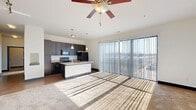 Located at 881 3rd Ave SW in Carmel, Indiana, this well-appointed 2-bedroom, 2-bathroom residence offers a thoughtfully designed single-floor layout. The open-concept living, dining, and kitchen area serves as the heart of the home, bathed in natural light streaming through expansive floor-to-ceiling sliding glass doors fitted with vertical blinds. Ceiling fans add both function and character to the space. The kitchen features dark cabinetry, a central island with a built-in sink, granite-style countertops, stainless steel appliances, and elegant pendant lighting overhead. Hardwood-style flooring transitions seamlessly into plush carpeting throughout the living and bedroom areas. The primary bedroom is a generous retreat, accessed through stylish sliding barn doors that open to a private en-suite bathroom. The bathroom is finished with a dark vanity, white countertops, tile flooring, and a soaking tub with large-format tile surround. A dedicated office and four closets — including a spacious walk-in — provide excellent storage. The secondary bedroom offers a ceiling fan and a large window with outdoor views. An in-unit laundry room with side-by-side washer and dryer completes this functional and modern residence.