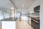 Located at 74 Curlew Dr in Toronto's M3A neighbourhood, this one-bedroom, one-bathroom unit offers a well-designed layout across a single floor. The open-concept kitchen and living area form the heart of the space, where a peninsula with a dark countertop provides a natural divide between the two zones. The kitchen is outfitted with white cabinetry, a herringbone tile backsplash, stainless steel appliances including a refrigerator, dishwasher, and range, and light tile flooring that contrasts with the warm parquet found throughout the rest of the unit. The living room is generously proportioned, featuring a wide bank of windows that invite ample natural light and offer views of surrounding greenery. A distinctive textured ceiling adds architectural character to this area. The bedroom is a comfortable size, complete with mirrored sliding closet doors, a window overlooking the outdoors, and baseboard heating. The bathroom is finished with classic white subway tile surrounding a full bathtub with an overhead shower, complemented by clean chrome fixtures. Consistent parquet flooring throughout the main living spaces ties the unit together with a timeless, cohesive aesthetic.