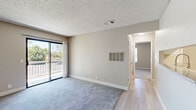 Located at 1370 W H St in Dixon, California, this one-bedroom, one-bathroom unit offers a well-organized single-floor layout designed for efficient, comfortable living. The space is thoughtfully arranged to maximize functionality across its living room, kitchen, bedroom, bathroom, and closet.

The living room features soft carpeting, neutral beige walls, and a textured ceiling. A sliding glass door leads to a private balcony with outdoor views of surrounding greenery, allowing natural light to fill the space. A wall-mounted ventilation panel adds a practical touch to the room's clean design.

The kitchen is outfitted with white upper cabinetry, grey lower cabinets, granite-look countertops, and light wood-style flooring. Stainless steel appliances, including a range and refrigerator, complete the functional galley-style layout.

The bedroom is a well-proportioned room with plush carpeting, a ceiling fan with a light fixture, a window with blinds offering natural light, and a sliding door providing additional outdoor access. The textured ceiling continues throughout, maintaining a consistent aesthetic.

The bathroom features light wood-style flooring, a granite-topped vanity, and a tub-shower combination equipped with assist grab bars. The overall ambiance of the unit is clean, neutral, and move-in ready.