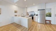 This contemporary 810 square foot apartment offers a harmonious blend of style and functionality. The space boasts three bedrooms, including a primary bedroom of 100 square feet, and two well-appointed bathrooms. The open-concept design creates a seamless flow between living areas, maximizing the use of space.

The kitchen is a highlight, featuring sleek white cabinetry, stainless steel appliances, and a practical island that doubles as a breakfast bar. The living room is bathed in natural light from floor-to-ceiling windows, offering breathtaking views of the surrounding area. Hardwood floors throughout add warmth and elegance to the space.

The bedrooms are thoughtfully designed with comfort in mind. The primary bedroom showcases a modern aesthetic with a textured headboard and artistic accents. The bathrooms are pristine, with one featuring a combination tub-shower and the other a spacious walk-in shower.

The apartment's design emphasizes clean lines and a neutral color palette, creating a calm and inviting atmosphere. Recessed lighting and strategically placed fixtures provide ample illumination. The inclusion of a compact workspace and ample storage solutions makes this apartment ideal for modern urban living.