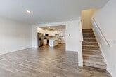 Located at 216 Meyers Ridge Rd in Cramerton, NC, this two-story home offers a well-designed layout across two floors. The main level features an open-concept living, dining, and kitchen area unified by durable hardwood-style flooring. The kitchen is a standout, outfitted with white shaker cabinetry, light quartz countertops, a central island with seating, and a full suite of stainless steel appliances including a French door refrigerator, electric range, over-the-range microwave, and dishwasher. A tile backsplash and recessed lighting complete the polished look. Carpeted stairs lead to the upper floor, where three bedrooms provide comfortable accommodations. The spacious primary bedroom includes direct access to a private bathroom and a dedicated closet. Additional bedrooms are bright and carpeted, each with natural light from windows and access to closet storage. Four closets throughout the home offer generous storage. A dedicated laundry room on the upper level houses a full-size washer and dryer. The home also includes an attached garage, a utility room housing the HVAC system, and three full bathrooms. Clean white walls and neutral finishes give the home a fresh, move-in ready appearance throughout.