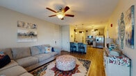 This single-floor residence offers a thoughtfully designed open-concept layout that connects the living room, dining area, and kitchen into one cohesive, functional space. The living room is generously sized, featuring wood-look plank flooring, a ceiling fan with light fixture, and multiple windows dressed with decorative curtains that allow natural light to fill the space. A sliding glass door provides access to an outdoor balcony, enhancing the sense of openness.

The kitchen is equipped with stainless steel appliances, including a French door refrigerator, range, built-in microwave, and dishwasher. Gray shaker-style cabinetry is paired with light granite countertops, and a peninsula with bar seating creates a practical dining and entertaining space. An adjacent laundry closet houses a stacked washer and dryer unit for added convenience.

The master bedroom is a standout feature, showcasing a tray ceiling, ceiling fan, plush carpeting, and natural light from multiple windows. The room offers generous space for large furniture and a seating area.

The bathroom includes a vanity with granite countertops, ample cabinetry, wood-look flooring, and a shower with curtain enclosure, maintaining the consistent, clean aesthetic found throughout the home.