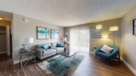 Located at 8000 Montgomery Blvd NE in Albuquerque, New Mexico, this single-floor residence offers a cohesive and thoughtfully designed interior with a neutral, modern aesthetic throughout. The living room serves as the centerpiece of the home, featuring durable wood-style flooring, a textured ceiling, and large sliding glass doors fitted with vertical blinds that allow abundant natural light to fill the space while providing access to an outdoor area. The kitchen is designed in a galley-style layout, showcasing dark espresso cabinetry, granite-style countertops, a classic subway tile backsplash, and black appliances including a refrigerator and range, all complemented by wood-style flooring that ties the spaces together. The bedroom is generously proportioned, offering wood-style flooring, a large window with vertical blinds for natural light, and a textured ceiling consistent with the rest of the home. A secondary room provides flexible space suitable for a den or additional bedroom, finished with plush carpet and neutral wall tones. The bathroom features a full tub-shower combination, dark wood vanity cabinetry, wood-style flooring, and tasteful fixtures. Throughout the residence, warm neutral tones and consistent finishes create a cohesive and inviting living environment.
