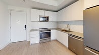 Unit 306 at 215 Park in Hallandale Beach, FL is a thoughtfully designed two-bedroom, two-bathroom residence offering a clean, contemporary aesthetic throughout. The single-level layout flows efficiently, connecting living and sleeping areas via a bright hallway accented by smooth white walls and light wood-style flooring that runs consistently through the unit.

The kitchen is a standout feature, outfitted with flat-front white cabinetry extending to the ceiling for generous storage, a marble-effect tile backsplash, neutral-toned countertops, a brass-finish undermount sink, and stainless steel appliances including a range, dishwasher, refrigerator, and built-in microwave.

Both bedrooms are bright and well-proportioned, benefiting from natural light through horizontal-blind-fitted windows that offer views of the surrounding Hallandale Beach skyline and greenery. One bedroom includes a ceiling fan with integrated lighting. A sliding barn-style door adds a modern architectural touch in the living area.

Each bathroom features striking marble-patterned porcelain tile on both the floors and shower/tub surrounds, paired with wood-toned floating vanities and matte black hardware, creating a polished, spa-like finish. The overall ambiance is clean, modern, and move-in ready.