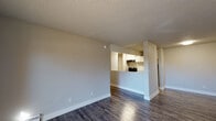 This 2-bedroom, 1-bathroom unit is thoughtfully laid out across a single floor, offering a comfortable and practical living environment. The open living area features durable wood-style flooring, neutral-toned walls, and a textured ceiling, creating a clean and understated aesthetic. A sliding glass door leads directly to a private balcony, filling the space with natural light and providing outdoor access with views of the surrounding area.

The kitchen is positioned adjacent to the living area and features a pass-through counter with granite-style countertops, white shaker cabinetry, black appliances including a range and refrigerator, and a modern brushed nickel faucet — making it both functional and visually cohesive.

Both bedrooms are generously proportioned with the same wood-style flooring and neutral finishes. One bedroom includes a window with a view of the outdoors and a baseboard heating unit, while the other provides a quiet, well-lit retreat. The hallway connects to a full bathroom equipped with a white vanity, granite-style countertop, undermount sink, brushed nickel fixtures, and a tub-shower combination. A linen closet with shelving is also accessible from the hallway, offering additional storage.