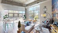 Located on Liberty Avenue in Pittsburgh's vibrant Bloomfield neighborhood, this one-bedroom, one-bathroom loft-style unit delivers an impressive blend of industrial architecture and eclectic interior design. The open-concept kitchen and living area is the heart of the home, anchored by dramatic floor-to-ceiling windows that flood the space with natural light and offer sweeping street-level views. Exposed concrete ceilings and wide-plank hardwood floors reinforce the industrial character, while a striking Pittsburgh skyline mural serves as a bold focal point in the living area. The kitchen features warm wood cabinetry, granite countertops, a breakfast bar with seating, and full appliances. A hallway lined with a large-scale cityscape mural connects the main living space to the private bedroom and bathroom. The bedroom is generously proportioned, highlighted by a vibrant mosaic-patterned accent wall, soaring ceilings, and a large window that continues the theme of abundant natural light. The bathroom features rich wood vanity cabinetry, hardwood flooring, a soaking tub, and eye-catching teal geometric accent walls. Two closets provide practical storage throughout. This unit offers a uniquely artistic and urban living experience.