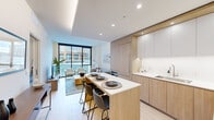 This single-floor unit offers a thoughtfully designed layout that maximizes functionality across its well-proportioned floor plan. The open-concept kitchen and living area forms the heart of the space, anchored by large floor-to-ceiling windows that flood the interior with natural light and provide views of the surrounding urban streetscape. Light hardwood flooring runs throughout, contributing to the unit's warm, cohesive aesthetic.

The kitchen is outfitted with light oak cabinetry paired with white upper cabinets and white quartz countertops. A built-in gas range, wall oven, and panel-ready refrigerator are integrated seamlessly into the cabinetry. A kitchen island with seating extends into the living area, defining the transition between cooking and lounging spaces.

The living area is compact yet comfortable, with space for a full seating arrangement oriented toward the expansive windows. A hallway connects the main living space to the private bedroom, which is a well-sized retreat with clean white walls and light flooring. A dedicated closet provides practical storage nearby.

The bathroom features large-format grey tile flooring, a floating white vanity with an extended mirror, and a separate shower area, all presented in a minimalist, contemporary style.