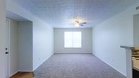 Located at 5400 Diamond Loch in Columbus, Ohio, this single-floor residence offers a clean, functional layout designed for comfortable everyday living. The living area features plush wall-to-wall carpeting underfoot and a textured ceiling fitted with a ceiling fan, creating a cozy and well-ventilated environment. A large window allows natural light to fill the space, enhancing its open and airy feel with neutral-toned walls that complement a variety of furnishing styles. The kitchen is a standout feature of the home, showcasing dark espresso cabinetry that contrasts elegantly with light countertops. A stylish mosaic tile backsplash adds a modern decorative touch, while track lighting overhead ensures the workspace is well-lit. The kitchen is equipped with a double-basin sink, an electric range, a refrigerator, and a built-in microwave, offering a fully functional cooking environment. Light hardwood-style flooring runs throughout the kitchen, adding warmth and easy maintenance. The overall design of this residence balances practicality with thoughtful finishes, making it a welcoming and move-in-ready space in the Columbus area.