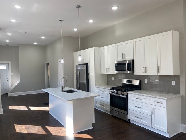 The kitchen features solid wood white cabinets, stainless steel appliances, and quartz countertops - 308 Center St