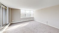 Located at 660 Boas St in Harrisburg, PA, this one-bedroom, one-bathroom unit offers a well-organized floor plan across a single level. The combined kitchen and living area forms the heart of the unit, with the living room featuring large windows and a sliding glass door that opens to a private balcony overlooking the Harrisburg cityscape. Abundant natural light fills the carpeted living space, which also includes a wall-mounted HVAC unit and baseboard heating. The kitchen is outfitted with white cabinetry, granite-style countertops, a gas range, dishwasher, and full-size refrigerator, all set on wood-style flooring with a window providing natural light and outdoor views. The bedroom is a comfortable, carpeted retreat with generous wall-to-wall closet space featuring bi-fold doors, offering ample storage. The bathroom retains a classic mid-century character, showcasing pink tile work throughout the shower surround and walls, complemented by a pedestal sink, a mirrored medicine cabinet, and a combination tub and shower. Neutral tones and clean white trim throughout the unit create a cohesive, understated aesthetic well-suited for urban living in downtown Harrisburg.