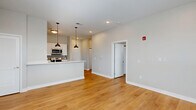 Located at 400 W Washington St in Muncie, Indiana, this well-appointed one-bedroom, one-bathroom unit offers a thoughtfully designed open-concept layout with warm hardwood-style flooring flowing consistently throughout every room. The living area is bright and airy, illuminated by recessed lighting and natural light, providing a welcoming atmosphere with ample space for comfortable furnishing. The kitchen is a standout feature, showcasing white shaker cabinetry, light quartz countertops, a subway tile backsplash, and a full suite of stainless steel appliances including a range, microwave, dishwasher, and refrigerator. A peninsula with pendant lighting creates a natural divide between the kitchen and living area, ideal for casual dining or entertaining. The bedroom offers a comfortable footprint with large windows fitted with blinds, a ceiling fan, and access to generous closet storage — with four closets distributed throughout the unit. The bathroom is finished with a quartz-topped vanity, a framed mirror, and a full tub-shower combination. A dedicated laundry area adds everyday convenience. Neutral tones and clean, modern finishes give the space a cohesive and move-in-ready aesthetic throughout.