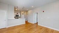 Located at 400 W Washington St in Muncie, Indiana, this well-appointed one-bedroom, one-bathroom unit offers a thoughtfully designed open-concept layout with warm hardwood-style flooring flowing consistently throughout every room. The living area is bright and airy, illuminated by recessed lighting and natural light, providing a welcoming atmosphere with ample space for comfortable furnishing. The kitchen is a standout feature, showcasing white shaker cabinetry, light quartz countertops, a subway tile backsplash, and a full suite of stainless steel appliances including a range, microwave, dishwasher, and refrigerator. A peninsula with pendant lighting creates a natural divide between the kitchen and living area, ideal for casual dining or entertaining. The bedroom offers a comfortable footprint with large windows fitted with blinds, a ceiling fan, and access to generous closet storage — with four closets distributed throughout the unit. The bathroom is finished with a quartz-topped vanity, a framed mirror, and a full tub-shower combination. A dedicated laundry area adds everyday convenience. Neutral tones and clean, modern finishes give the space a cohesive and move-in-ready aesthetic throughout.