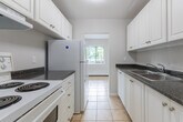 Located at 940 Commissioners Rd in London, Ontario, this 2-bedroom, 1-bathroom unit offers a practical and comfortable single-floor layout. The interior features light-toned vinyl plank flooring throughout, paired with neutral, soft-grey walls and clean white baseboards that create a fresh, cohesive aesthetic across all rooms.

The living room provides a generous open area filled with natural light, enhanced by baseboard heating units positioned beneath windows that offer views of surrounding greenery. The kitchen is equipped with white cabinetry featuring brushed nickel hardware, dark granite-style countertops, a coil-top electric range with overhead ventilation, and ample upper storage — a functional space designed for everyday use.

Both bedrooms are well-proportioned, with the primary bedroom offering a comfortable footprint suitable for a full bedroom suite. Each room benefits from the consistent flooring and neutral palette, lending a calm and versatile atmosphere. Windows in the bedrooms allow for natural light and outdoor views.

The bathroom is finished with bright white tile surrounding a full soaker tub and shower combination, complemented by chrome fixtures, maintaining a clean and practical design. Overall, this unit presents a tidy, move-in-ready space with a consistent modern-neutral finish throughout.