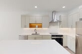 Located at 1801 N Beauregard St in Alexandria, Virginia, this thoughtfully designed one-bedroom, one-bathroom residence offers a clean, modern aesthetic throughout. The open-concept living and dining area is bathed in natural light through large floor-to-ceiling windows, with light wood-tone flooring lending warmth to the bright, white interior. Sliding glass doors lead to a private balcony overlooking a lush, tree-lined courtyard with well-maintained green space — a tranquil outdoor retreat.

The contemporary kitchen is a standout feature, showcasing soft sage-toned cabinetry extending to the ceiling, white quartz countertops, a subway tile backsplash, a matte black undermount sink, and stainless steel appliances including a range with a wall-mounted hood, dishwasher, and full-sized refrigerator. A central island with a warm wood base provides additional workspace and casual seating.

The bedroom is generously proportioned, filled with natural light from multiple windows offering views of the surrounding greenery and building exterior. The bathroom features tile flooring, a white quartz vanity, and a backlit mirror. A dedicated closet, entrance foyer, hallway, and in-unit laundry areas complete this well-appointed residence, offering both comfort and functionality in a modern Alexandria setting.