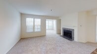 Located at 205 Century Ok in Alexandria, Virginia, this single-floor residence offers a thoughtfully designed open-concept layout filled with natural light. The spacious living room serves as the heart of the home, anchored by a classic tile-surround fireplace and flanked by large windows that invite abundant daylight. Plush wall-to-wall carpeting runs throughout the living and bedroom areas, adding warmth and comfort underfoot. A separate windowed nook adjacent to the living room provides a bright, versatile space ideal for dining or a reading area.

The kitchen is efficiently laid out with white cabinetry, granite-style countertops, a tiled backsplash, and tile flooring. It features a full suite of white appliances including a range, microwave, dishwasher, and refrigerator, along with a stainless steel sink. A pass-through counter opening connects the kitchen to the main living area, enhancing the open feel.

The bedroom is generously sized with soft carpeting and a sliding glass door that opens to a private outdoor balcony overlooking lush greenery, complemented by a ceiling fan for added comfort. The bathroom is well-appointed with granite-style countertops, white cabinetry, tile flooring, and a shower-tub combination. A dedicated in-unit stacked washer and dryer closet adds everyday convenience to this well-rounded Alexandria residence.