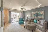 Located at 4017 Lake Ridge Circle in Virginia Beach, Virginia, this single-floor residence presents a thoughtfully designed layout with a consistent teal and gray color palette carried throughout the home. The living room serves as a central gathering space, distinguished by a tray ceiling with a ceiling fan, plush carpeting, and a soft blue-gray accent wall. Natural light filters in through windows dressed with sheer curtains, creating a bright and welcoming ambiance.

Adjacent to the living room, the dining area features a tray ceiling detail overhead and opens directly into the kitchen, which is equipped with warm honey-toned cabinetry, dark granite-style countertops, tile flooring, and white appliances including a range, built-in microwave, and refrigerator.

The bedrooms each offer plush carpeting and distinct accent walls. The primary bedroom features a deep slate-blue accent wall and provides access to closets, while a secondary bedroom showcases a vivid teal accent wall with natural light from a window overlooking outdoor greenery.

Both bathrooms include tub-shower combinations with tile flooring and clean, neutral finishes. Throughout, the home maintains a cohesive and carefully coordinated aesthetic.