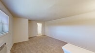 This single-floor, one-bedroom, one-bathroom unit offers a practical and efficiently organized layout across a compact but well-utilized footprint. The combined kitchen and living area forms the heart of the unit, with the kitchen featuring warm honey-toned wood cabinetry, ample upper and lower storage, granite-style countertops, a single-basin sink, and white appliances including a gas range, dishwasher, microwave, and refrigerator. The floor in this area is finished with neutral ceramic tile. A pendant light fixture and flush-mount ceiling light provide functional illumination throughout.

The living area transitions seamlessly from the kitchen and is carpeted in a warm beige tone, offering a comfortable and open feel. A wall-mounted air conditioning unit and a window with horizontal blinds provide natural light and climate control.

The bedroom is a well-proportioned space with soft carpet flooring, a window overlooking the outdoors, and a ceiling light fixture. It connects to a dedicated walk-in closet fitted with full-perimeter hanging rods and tile flooring, offering substantial storage capacity.

The bathroom includes a full-size soaking tub and shower combo with clean white subway tile surround, a chrome curtain rod, toilet, and vanity. A hallway connects the primary spaces, contributing to an organized and functional flow throughout the unit.