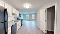 This 2-bedroom, 1-bathroom residence offers a thoughtfully laid-out single-floor plan that maximizes functionality and comfort. The open-concept kitchen and living area serves as the heart of the unit, featuring white shaker-style cabinetry, light quartz countertops, a stainless sink, and a full suite of black appliances including a refrigerator, electric range, microwave, and dishwasher. The living area extends naturally from the kitchen, bathed in natural light from dual windows and complemented by a ceiling fan overhead. Light wood-style vinyl plank flooring flows seamlessly throughout the main living spaces, creating a cohesive and clean aesthetic. Neutral gray walls provide a versatile backdrop throughout the unit. Both bedrooms are generously proportioned, each equipped with individual wall-mounted mini-split HVAC units for personalized climate control and ceiling fans for added comfort. The primary bedroom includes a dedicated closet outfitted with wire shelving for organized storage. A second closet offers additional storage capacity. The bathroom features a full tub-shower combination with tile surround and tile flooring. Two hallways connect the living spaces to the private quarters, and the overall layout is efficient and well-organized, making this a practical and inviting living space.