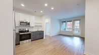 This well-appointed 2-bedroom, 2-bathroom residence in Kansas City's vibrant Crossroads district offers a thoughtfully designed single-floor layout. The open-concept kitchen and living area serves as the heart of the home, featuring light hardwood-style flooring, recessed lighting, and large windows that invite abundant natural light. The kitchen is outfitted with stainless steel appliances—including a refrigerator, range, microwave, and dishwasher—complemented by two-tone cabinetry in white and gray, a classic subway tile backsplash, and a stainless steel sink.

The primary bedroom is generously sized with direct access to a private outdoor area through a glass door, hardwood-style flooring, and large windows framing urban views. The second bedroom features plush carpet, a wide window with city views, and ample space. Three closets, including a walk-in with wire shelving, provide excellent storage throughout.

Both bathrooms are finished with gray shaker-style vanities, quartz-style countertops, wood-look flooring, and subway tile tub surrounds with matte black hardware accents. Additional conveniences include a dedicated laundry area and a utility room. The clean, modern aesthetic is consistent throughout, creating a cohesive and comfortable living environment.