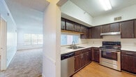 This single-floor 2-bedroom, 2-bathroom residence offers a practical and comfortable layout designed for everyday living. The kitchen is well-appointed with dark espresso cabinetry, light countertops, stainless steel appliances including a dishwasher and range with overhead ventilation, and wood-look flooring. A window above the sink brings in natural light, while the open pass-through connects seamlessly to the carpeted living area beyond.

The living and dining spaces feature neutral carpet, wainscoting-style wall detailing, and a ceiling fan with integrated lighting. Built-in shelving adds a decorative touch, and a doorway leads further into the private areas of the home.

Both bedrooms are generously sized, each featuring plush carpet, large windows with outdoor tree views, and ample wall space. One bedroom includes a ceiling fan and the other offers a spacious closet with bifold doors.

The two bathrooms are consistent in design, each featuring dark wood vanities, light countertops, large mirrors with bar lighting, and wood-look flooring. One bathroom includes a full tub-shower combination with tiled surround, while the other provides a streamlined vanity and toilet layout. Together, the rooms create a cohesive, functional living environment.