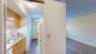 Located at 2920 Dean Parkway in Minneapolis, Minnesota, this one-bedroom, one-bathroom unit offers a practical and comfortable single-floor layout. The living room is a bright, open space finished with wood-style plank flooring and clean white walls, with multiple windows along one side that bring in generous natural light and offer views of surrounding greenery. A window air conditioning unit and baseboard heating provide year-round climate control. The kitchen features a peninsula counter that separates it from the living area, wood-tone cabinetry, and a window that further enhances the sense of openness. The bedroom is a well-proportioned room finished with plush carpeting, a ceiling fan with light fixture, and a wide sliding-door closet for ample storage. A second door in the bedroom provides additional access. The bathroom is finished with classic white square tile surrounding a full bathtub and shower combination, accented by chrome fixtures for a clean, timeless look. Throughout the unit, the neutral color palette and consistent finishes create a cohesive, move-in-ready atmosphere suited for comfortable everyday living.