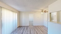 Located at 6424 Iron Horse Blvd in North Richland Hills, TX, this one-bedroom, one-bathroom unit offers a practical and well-appointed single-floor layout. The combined kitchen and living area serves as the heart of the home, featuring light-toned wood-look vinyl plank flooring, a textured ceiling, and a ceiling fan with integrated lighting. A sliding glass door fitted with vertical blinds brings in generous natural light and provides outdoor access. The kitchen is defined by a pass-through breakfast bar, dark cabinetry, mosaic tile backsplash, and black appliances, giving it a clean, modern contrast. A dedicated laundry closet with a full-size washer and dryer is conveniently situated nearby. The bedroom is carpeted for comfort and is well-sized, featuring a window with natural light, a textured ceiling, and direct access to both a walk-in closet and the full bathroom. The bathroom includes a full tub-shower combo with white tile surround and updated dark vanity cabinetry. Throughout the unit, neutral wall tones and consistent finishes create a cohesive and move-in ready living environment.