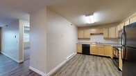 This well-appointed 3-bedroom, 2-bathroom unit at 4274 University Ave in Grand Forks, ND offers a comfortable and functional single-floor layout. The open-concept kitchen and dining area is equipped with light wood cabinetry, ample counter space, a double-basin sink, and black appliances including a dishwasher, range, and refrigerator. Durable vinyl plank flooring runs throughout the main living areas, lending a clean, modern feel. The spacious living room is a highlight, featuring large sliding glass doors with vertical blinds that open to an outdoor balcony, filling the room with natural light and providing views of the surrounding neighborhood. Three well-sized bedrooms are finished with plush carpeting and individual windows that bring in additional natural light. The primary bedroom offers a comfortable, generously proportioned layout. Two full bathrooms each include a tub/shower combo with clean, white surrounds. Baseboard heating is present throughout, ensuring warmth during North Dakota winters. The unit also includes a dedicated laundry area and an impressive five closets, providing exceptional storage throughout. Neutral warm-toned walls and textured ceilings complete the move-in-ready interior.