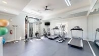 Located at 4475 River Birch Loop in High Point, NC, this dedicated fitness center offers a thoughtfully designed workout environment within a compact but efficiently utilized footprint. The space is finished with crisp white walls, elegant crown molding, and recessed lighting complemented by a ceiling fan, creating a bright and comfortable atmosphere for exercise.

The main workout area features durable rubber tile flooring throughout, providing both safety and resilience underfoot. A large wall-to-wall mirror along one side of the room visually expands the space while allowing users to monitor their form during workouts. Multiple cardio machines, including treadmills and an elliptical trainer, are neatly arranged and face a wall-mounted flat-screen television for entertainment during sessions. A professional-grade cable cross machine anchors one corner of the room, offering a wide range of strength training exercises. An arched window adjacent to the cable machine floods that area with natural light, adding an airy quality to the space.

The entry area features dark slate-style tile flooring, dark-framed French doors with frosted glass panes, and a sleek white console table for storing accessories such as yoga mats. A glass exterior door provides direct outdoor access, enhancing ventilation and convenience. Overall, this fitness center is designed to deliver a clean, functional, and welcoming environment for daily exercise.