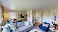 This single-floor residence offers a thoughtfully designed layout that balances comfort and style throughout. The open-concept living and dining area serves as the heart of the home, featuring warm hardwood flooring, crown molding, and an abundance of natural light streaming through large windows that frame lush green outdoor views. The living space accommodates a generous seating arrangement and flows seamlessly into a dedicated dining area, creating an ideal setting for both relaxing and entertaining.

The galley-style kitchen is both functional and refined, showcasing light gray shaker cabinetry with brass hardware, crisp white quartz countertops, classic subway tile backsplash, and a striking black-and-white octagonal tile floor. Stainless steel appliances complete the well-equipped space.

The two bedrooms are bright and serene, each benefiting from hardwood floors, crown molding, and generous natural light. The primary bedroom features dual windows with garden views, while both rooms offer a calm, restful ambiance.

The bathroom maintains a timeless aesthetic with its classic black-and-white octagonal mosaic tile floor, pedestal sink with brass fixtures, a full soaking tub, and clean white wainscoting — all combining to create a charming, vintage-inspired retreat. Throughout the residence, a cohesive neutral palette with warm wood tones and mid-century modern accents lends the space an inviting and polished character.