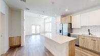 Located at 1830 Homerun Rd in Kissimmee, FL, this well-appointed 2-bedroom, 2-bathroom residence offers a thoughtfully designed open-concept layout flooded with natural light. The living, dining, and kitchen areas flow seamlessly together beneath soaring ceilings, with large transom windows and French doors leading to a private balcony that overlooks lush outdoor greenery. Light-toned hardwood-style flooring runs throughout, enhancing the bright and airy atmosphere.

The kitchen is a functional centerpiece, featuring a large white quartz island, a full suite of stainless steel appliances including a French door refrigerator, a subway tile backsplash, and a combination of white upper cabinets and warm wood-toned lower cabinetry. A pantry and dedicated laundry area add everyday convenience.

The primary bedroom is generously sized with soaring ceilings and tall windows that maximize natural light. Its en-suite bathroom includes a dual-sink vanity with quartz countertops, wood-toned cabinetry, a tiled walk-in shower, and clean modern fixtures. Four closets throughout the home provide ample storage. Additional spaces include a dedicated office and utility room, rounding out a highly functional and modern floor plan.