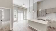 Located at 309 W Front St in the heart of Traverse City, Michigan, this thoughtfully designed one-bedroom, one-bathroom unit offers a bright and contemporary living experience. The open-concept layout seamlessly connects the kitchen, dining, and living areas, all finished with light-toned luxury vinyl plank flooring and bathed in natural light from large sliding glass doors and windows dressed with vertical blinds.

The kitchen is a standout feature, showcasing gray shaker-style cabinetry extending to the ceiling, gleaming white quartz countertops, a classic subway tile backsplash, a stainless steel undermount sink, and a full suite of stainless steel appliances. A kitchen island provides additional prep and dining space, illuminated by a trio of elegant glass pendant lights.

The dining and living areas benefit from soaring ceilings and an abundance of natural light, creating an airy, spacious ambiance enhanced by a ceiling fan. The generously sized bedroom is carpeted for warmth and comfort, with a large window that draws in natural light.

The bathroom features a long vanity with dual sinks, quartz counters, gray cabinetry, and wood-look flooring. A walk-in closet with wire shelving and hanging rods completes this well-appointed unit, offering practical storage solutions in a clean, modern finish.