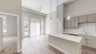 Located at 309 W Front St in the heart of Traverse City, Michigan, this thoughtfully designed one-bedroom, one-bathroom unit offers a bright and contemporary living experience. The open-concept layout seamlessly connects the kitchen, dining, and living areas, all finished with light-toned luxury vinyl plank flooring and bathed in natural light from large sliding glass doors and windows dressed with vertical blinds.

The kitchen is a standout feature, showcasing gray shaker-style cabinetry extending to the ceiling, gleaming white quartz countertops, a classic subway tile backsplash, a stainless steel undermount sink, and a full suite of stainless steel appliances. A kitchen island provides additional prep and dining space, illuminated by a trio of elegant glass pendant lights.

The dining and living areas benefit from soaring ceilings and an abundance of natural light, creating an airy, spacious ambiance enhanced by a ceiling fan. The generously sized bedroom is carpeted for warmth and comfort, with a large window that draws in natural light.

The bathroom features a long vanity with dual sinks, quartz counters, gray cabinetry, and wood-look flooring. A walk-in closet with wire shelving and hanging rods completes this well-appointed unit, offering practical storage solutions in a clean, modern finish.