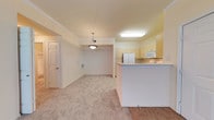 Located at 902 Milwaukee Ave in Lubbock, TX, this single-story residence offers a thoughtfully arranged open-concept floor plan that seamlessly connects the kitchen, dining, and living areas. The kitchen is equipped with light wood cabinetry, a white refrigerator, built-in microwave, and a breakfast bar peninsula that provides both additional prep space and a natural division between the kitchen and the adjoining living areas. Tile flooring anchors the kitchen zone, transitioning into plush, neutral-toned carpeting that extends throughout the dining and living spaces. The dining area is defined by a stylish pendant light fixture and crown molding details that add a refined architectural touch to the space. Walls are finished in soft, warm neutral tones that contribute to a bright and welcoming ambiance. A thermostat and ventilation registers are conveniently positioned, and interior doors lead to additional rooms, suggesting a well-organized layout. The consistent use of crown molding, clean white trim, and coordinated finishes throughout creates a cohesive and comfortable atmosphere, making this single-floor residence a practical and inviting place to call home.