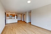 Located at 429 Peterson Rd in Burlington, WA, this well-appointed 3-bedroom, 2-bathroom unit offers a thoughtfully designed single-floor layout. The open-concept living and kitchen area serves as the heart of the home, showcasing a sleek kitchen with warm wood-toned cabinetry, stainless steel appliances including a refrigerator, gas range, and microwave, and a generous island topped with striking veined quartz countertops. Pendant lighting adds a modern touch over the island, which also features a built-in sink. Light oak-toned hardwood flooring flows consistently throughout the entire unit, lending warmth and visual continuity to every room. The living area benefits from abundant natural light through large windows that frame views of the surrounding neighborhood and distant mountains. Each of the three bedrooms is well-proportioned, with the primary bedroom offering comfortable space and bright window views. The two bathrooms are clean and functional, featuring a tub-shower combination and matching light flooring. An in-unit washer and dryer area adds practical convenience. The overall aesthetic is contemporary and neutral, creating a versatile and move-in-ready living environment.