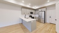 Located in Heber City, Utah, this well-appointed three-story home offers four bedrooms and four bathrooms across three thoughtfully designed floors. The main level features an open-concept layout combining the dining room, kitchen, and living area, all unified by light hardwood flooring and recessed lighting. The kitchen is equipped with stainless steel appliances — including a French door refrigerator, electric range, and over-the-range microwave — complemented by gray shaker-style cabinetry with black hardware, white subway tile backsplash, and a kitchen island. A welcoming entryway with a sidelight door and clean white walls sets the tone for the home's modern aesthetic. The bathrooms showcase marble-look tile flooring, white subway tile tub surrounds, gray vanities with white countertops, and sleek matte black fixtures. Bedrooms feature plush carpeting and ample closet space, including double doors in the primary bedroom. A dedicated laundry room houses a full-size washer and dryer on tile flooring. Additional highlights include a utility room, six closets, and three staircases connecting each level. The home's consistent use of white walls, black hardware accents, and mixed hard and soft flooring surfaces creates a clean, contemporary feel throughout.