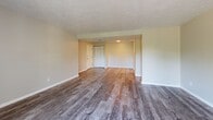 Located at Abbeyville Road in Pittsburgh, PA 15228, this one-bedroom, one-bathroom unit offers a well-organized layout across a single floor. The open living area features durable hardwood-style plank flooring and a textured ceiling, creating a clean and neutral aesthetic. A large sliding glass door fills the space with natural light and provides direct access to a private balcony, offering pleasant outdoor views. The kitchen is positioned adjacent to the living area and includes white cabinetry, a range, and a practical pass-through design that maintains a connected feel throughout the main living space. The generously sized bedroom is carpeted for comfort, featuring a textured ceiling, a window with outdoor views, and two doorways — one leading to the hallway and another to a dedicated walk-in closet. The walk-in closet provides ample storage with double hanging rods and carpeted flooring. The full bathroom is finished with wood-style flooring, a white vanity with under-cabinet storage, a toilet, and a tub/shower combination with a curtain rod. Throughout the unit, neutral tones and clean finishes contribute to a move-in-ready atmosphere that is both functional and easy to personalize.