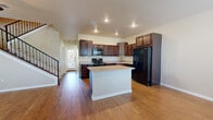 This two-story home offers a well-designed layout that balances open communal spaces with comfortable private retreats. The main level features warm hardwood flooring throughout, anchored by a bright and open living area with a ceiling fan and multiple windows that invite natural light. A striking staircase with black iron balusters connects the two floors, adding a refined architectural detail to the main living space.

The kitchen is a functional centerpiece, equipped with rich dark wood cabinetry, light granite countertops, and a full suite of black appliances including a gas range, built-in microwave, dishwasher, and refrigerator. A central island with a matching granite surface provides additional prep space and casual dining options. Recessed lighting overhead keeps the kitchen bright and practical.

Upstairs, the bedrooms are carpeted for comfort and feature mirrored sliding closet doors that enhance the sense of space. The primary suite is particularly well-appointed, with a dual-sink vanity topped with granite, dark wood cabinetry, and direct access to a spacious walk-in closet outfitted with built-in shelving and hanging rods. Secondary bedrooms also include mirrored closets with dedicated shelving. The home's neutral color palette and consistent finishes throughout create a cohesive, move-in-ready environment.