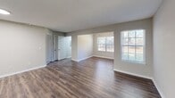 Located at 3101 Washington Ridge Way in Knoxville, TN, this single-floor residence offers a practical and modern layout across one bedroom, a combined kitchen and living area, a utility room, and a closet. Rich, dark-toned hardwood-style flooring flows throughout the main living spaces, creating a warm and cohesive aesthetic. The open-concept living room is generously proportioned with neutral gray walls, crisp white trim, and multiple windows that allow ample natural light to fill the space. A ceiling fan with a built-in light fixture is installed in the living area, adding both function and style. The kitchen is designed for efficiency, featuring white shaker-style cabinetry with sleek dark hardware, light granite countertops, stainless steel appliances including a refrigerator and range, a dishwasher, and durable wood-look flooring. A pass-through counter connects the kitchen to the living area, enhancing the open feel. The bedroom offers comfortable carpeted flooring, a ceiling fan, a window with natural light, a closet, and direct access to a private bathroom complete with a vanity and mirror. Textured ceilings are present throughout, and the overall design reflects a clean, move-in-ready condition.