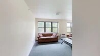 Located at 109 Dryden Rd in Ithaca, NY, this 4-bedroom, 2-bathroom unit offers a well-organized single-floor layout designed to comfortably accommodate multiple residents. The living room is bright and welcoming, featuring large black-framed windows that frame views of surrounding greenery, soft carpeted flooring, and a wall-mounted AC unit. It flows naturally into a dedicated dining area, also carpeted and lit by a generous window overlooking the neighborhood. The kitchen is efficiently laid out with white cabinetry accented by warm wood trim, light tile flooring, a double sink, dishwasher, and ample counter and storage space. Each of the four bedrooms is modestly sized with carpeted floors, natural light from windows with blinds, and individual wall AC or baseboard heating units. The primary bedroom offers slightly more space with room for a dresser and seating. Both bathrooms share a consistent design featuring light tile flooring, a vanity with storage, a toilet, and a tub-shower combination with a sliding glass door. Three hallways connect the rooms efficiently throughout the unit, contributing to a functional and straightforward floor plan suited for shared living in the heart of Ithaca.