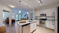 This single-floor residence offers a thoughtfully designed layout encompassing two bedrooms, two bathrooms, a utility room, and two closets connected by a central hallway. The open-concept kitchen and living area forms the heart of the home, where a central island with granite countertops and a stainless steel undermount sink serves as a functional focal point. Pendant lighting illuminates the island, complementing the stainless steel appliances, including a range, over-the-range microwave, and dishwasher. Light-toned cabinetry with sleek hardware lines the kitchen walls, providing ample storage.

The living area flows naturally from the kitchen and features wood-style flooring, a ceiling fan, and French doors that invite natural light and outdoor views. Each bedroom includes wood-style flooring, a ceiling fan, and window treatments. The primary bedroom features its own closet and dedicated bathroom access. Both bathrooms are finished with granite-topped vanities, light wood cabinetry, large-format tile flooring, and a soaking tub. The walk-in closet includes wire shelving for organized storage throughout.