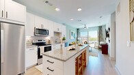 This thoughtfully designed one-bedroom, one-bathroom residence offers a efficient and functional single-floor layout. The open-concept kitchen is a standout feature, outfitted with crisp white shaker cabinetry, granite countertops, a subway tile backsplash, and a full suite of stainless steel appliances including a side-by-side refrigerator, electric range, built-in microwave, and dishwasher. A central island with seating provides additional workspace and a natural transition into the living area.

The living room is bright and inviting, bathed in natural light from large sliding glass doors that open to a private balcony with open outdoor views. A ceiling fan adds comfort, and light-toned hardwood-style flooring runs throughout the main living spaces.

The bedroom offers plush carpeting, multiple windows for natural light, a dedicated closet, and direct access to the bathroom. The bathroom features wood-look flooring, granite-topped white vanity cabinetry, and a shower with a curtain enclosure.

A hallway connects the main living areas to the private spaces, maintaining a clear and practical flow throughout. The overall aesthetic is clean and contemporary, characterized by a soft, neutral color palette and modern finishes throughout.