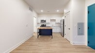This 500 square foot apartment offers a thoughtful blend of functionality and style within its compact footprint. The space is efficiently designed with one bedroom and one bathroom, making it ideal for a single occupant or couple.

The kitchen is a standout feature, boasting crisp white cabinetry, stainless steel appliances, and ample counter space. A central island with a wood top adds extra preparation area and casual dining space. Light wood-look flooring throughout creates a cohesive and airy feel.

The bedroom, measuring 100 square feet, is carpeted for comfort and features a large window that floods the space with natural light and offers urban views. Built-in closet space ensures adequate storage.

The bathroom is sleek and modern, with a white color scheme that enhances the sense of cleanliness. It includes a combination tub-shower unit, toilet, and likely a vanity (though not visible in the provided images).

Recessed lighting and neutral wall colors contribute to the apartment's bright and contemporary ambiance. The open-concept layout maximizes the use of space, with the kitchen flowing seamlessly into the living area.

Overall, this apartment combines modern aesthetics with practical living spaces, offering a comfortable urban dwelling in a compact package.