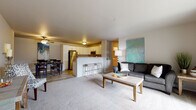 This single-floor unit in Marshfield, Wisconsin offers a well-designed open-concept layout that seamlessly connects the kitchen, dining, and living areas. The kitchen is outfitted with stainless steel appliances, including a refrigerator, range, and microwave, complemented by white cabinetry, light granite-style countertops, and wood-look flooring. A peninsula with bar seating provides additional functionality and visually anchors the space. The adjacent dining area features wood-look flooring and a ceiling fan, creating a comfortable setting for everyday meals. The living room is carpeted and opens to a private balcony through a sliding glass door, allowing natural light to fill the space. Two bedrooms offer plush carpet, neutral tones, and ample room for furnishings. One bedroom includes a window overlooking the exterior, enhancing its airy feel. The bathroom is finished with white cabinetry, granite-style counters, wood-look tile flooring, and a walk-in shower. A dedicated in-unit laundry area with a full-size washer and dryer adds everyday convenience. The overall aesthetic is clean, modern, and functional throughout.