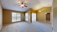 This efficient single-story home offers a thoughtfully designed layout that makes excellent use of its space. The open-concept living room and kitchen area serves as the heart of the home, where vaulted ceilings with a textured finish add a sense of height and openness. A ceiling fan with pendant lighting anchors the living space, which features plush carpeting, warm neutral-toned walls, and a sliding glass door fitted with vertical blinds that invites natural light and provides outdoor access. Multiple windows further brighten the living area, enhancing the airy feel of the vaulted ceiling.

The kitchen is outfitted with white cabinetry, granite-look countertops, a double-basin sink, and a full suite of black appliances, including a refrigerator and dishwasher. Wood-look flooring runs through the kitchen and connects to the dedicated laundry room, which accommodates a full-size washer and dryer side by side.

The spacious bedroom features carpeting, a ceiling fan, a textured ceiling, and a window offering natural light. A closet provides dedicated storage. The bathroom includes a full tub-shower combination with white tile surround and wood-look flooring. This home offers a practical and comfortable layout suited for everyday living.