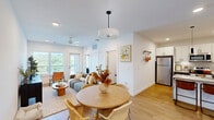 Located on High Mountain Road in Huntsville, Alabama, this thoughtfully designed one-bedroom, one-bathroom residence offers a clean, modern aesthetic with an efficient and well-appointed layout. Light wood flooring flows throughout the space, complementing the bright white walls and contemporary finishes that define the interior.

The open-concept kitchen and living area serves as the heart of the home. The kitchen features granite countertops, gray lower cabinetry paired with crisp white upper cabinets, a subway tile backsplash, stainless steel appliances including a refrigerator, microwave, and range, and a peninsula with seating illuminated by sleek pendant lighting. The adjacent living room is bathed in natural light from large windows and includes a ceiling fan overhead.

The bedroom is a serene retreat with large windows offering open outdoor views, generous natural light, and a dedicated closet for storage. Minimalist wall sconces and clean lines contribute to a calm, restful atmosphere.

The bathroom is well-designed with gray cabinetry, a dark countertop, an under-mount sink with matte black fixtures, and a full tub-shower combination framed by white tile. A patterned floor mat adds a subtle decorative touch. The overall ambiance of this residence is modern, airy, and move-in ready.