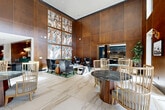 Located at 1950 Winrock Blvd in Houston, Texas, this single-floor amenity space spans an impressively large footprint, offering residents a comprehensive suite of upscale facilities across 12 distinct areas. The grand lobby serves as the centerpiece, distinguished by soaring double-height ceilings, floor-to-ceiling warm wood-paneled walls, and expansive white marble-veined tile flooring. A bold, large-scale abstract art installation commands the main wall, while a reception desk finished with brass accent lamps sets an elegant tone. Adjacent lounge areas feature plush seating arrangements, plaid-upholstered banquette nooks, and sophisticated décor that blend comfort with refined style. Glass-enclosed conference and co-working rooms provide professional-grade meeting spaces, complete with oval tables, leather chairs, and curated artwork. Private study nooks with marble desktop surfaces, herringbone tile flooring, and brass task lighting offer quiet individual workspaces. The fully equipped fitness center showcases hardwood floors, floor-to-ceiling mirrored walls, a comprehensive free-weight area, and bold decorative wallcoverings. Outdoors, a resort-style pool courtyard is framed by the multi-story residential building, offering ample lounge seating, pergola-shaded areas, lush landscaping, and a spacious sundeck—providing a tranquil retreat within an urban setting.