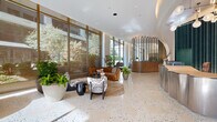 Located at 44 M St NE in Washington, DC, this expansive lobby is a masterclass in contemporary design. Spanning a generous single floor, the space immediately impresses with its polished terrazzo flooring, which transitions seamlessly into light herringbone hardwood parquet in connecting corridors. Floor-to-ceiling glazing along the perimeter floods the interior with abundant natural light and frames views of the surrounding urban streetscape and mature trees.

The reception area is anchored by a sculptural brushed-metal desk set against a dramatic backdrop of deep emerald fluted paneling, framed by a sweeping arched soffit with integrated cove lighting. Curved walls clad in warm-toned fluted wood panels guide visitors through the hallway, where arched doorways and recessed niches add architectural depth and rhythm.

A striking teal-tiled structural column rises prominently near a staircase finished in matching aquamarine terrazzo, becoming a bold artistic focal point. Curated lounge seating areas with organic forms, lush potted greenery, and carefully selected art pieces—including a large circular mixed-media wall installation—contribute to a refined, gallery-like ambiance. The overall design balances warm natural materials with cool metallic accents, creating a sophisticated and welcoming environment.