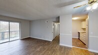 This single-floor unit offers a practical and comfortable layout with a clean, neutral aesthetic throughout. The main living area is spacious and inviting, finished with rich hardwood-style flooring and neutral gray walls that create a bright, open feel. A large sliding glass door floods the room with natural light and opens to a private balcony with outdoor views. A ceiling fan adds both functionality and a touch of warmth to the space. The textured ceilings are consistent throughout the unit, adding a classic residential character.

The kitchen is efficiently designed, featuring white cabinetry, granite-style countertops, and black appliances including a refrigerator, electric range with overhead ventilation, providing everything needed for everyday cooking. Adjacent hallways with louvered closet doors offer generous storage options.

The bedrooms are well-sized and carpeted for added comfort, with neutral walls and windows that bring in natural light. The bathroom is cleanly finished with wood-style flooring, a vanity with a light countertop, and a full tub-shower combination with white tile surround. A walk-in style closet area is conveniently accessible from the bathroom, enhancing the overall storage and utility of the space.